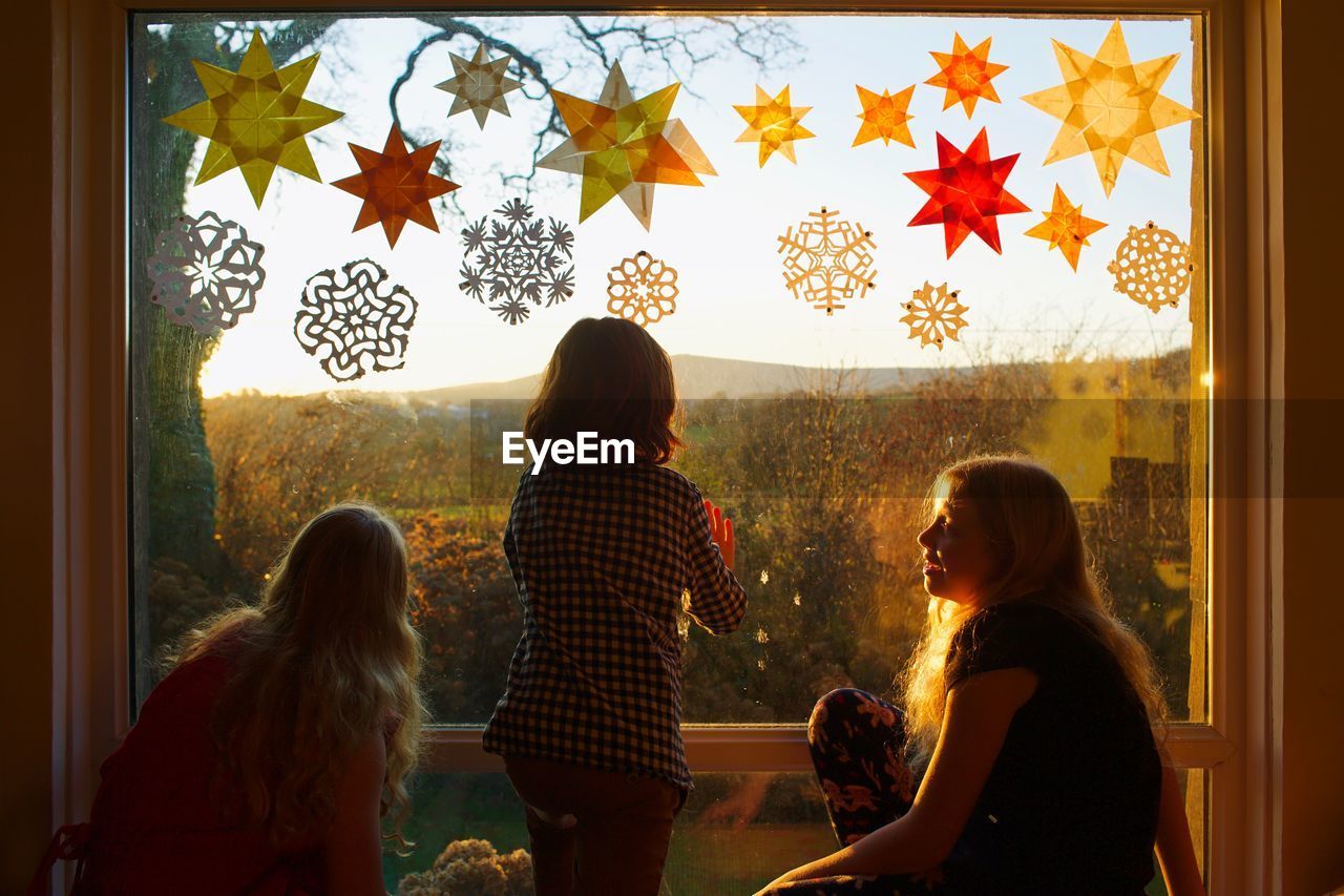 Siblings sitting against window glass