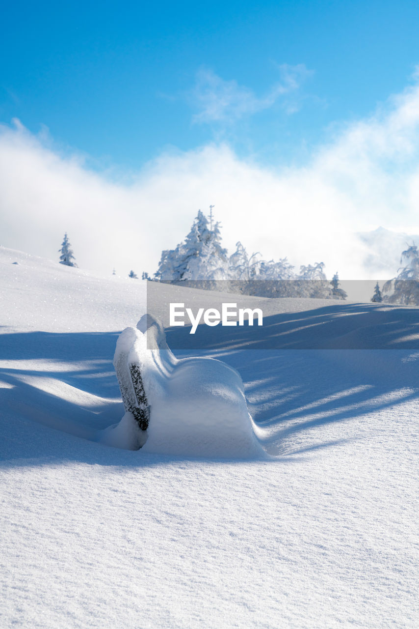 Frozen park bench covered in deep snow in beautiful winter wonderland, salzburg, austria.