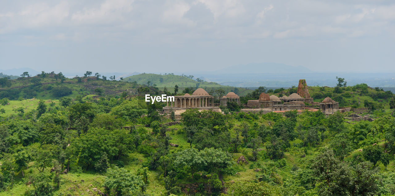 plant, architecture, tree, hill, built structure, building, building exterior, nature, sky, land, landscape, environment, scenics - nature, cloud, history, no people, green, beauty in nature, travel destinations, growth, the past, house, rural area, travel, outdoors, residential district, tourism, day, religion, field, tranquility, ancient, rural scene, forest, city, agriculture, foliage, lush foliage, place of worship, high angle view
