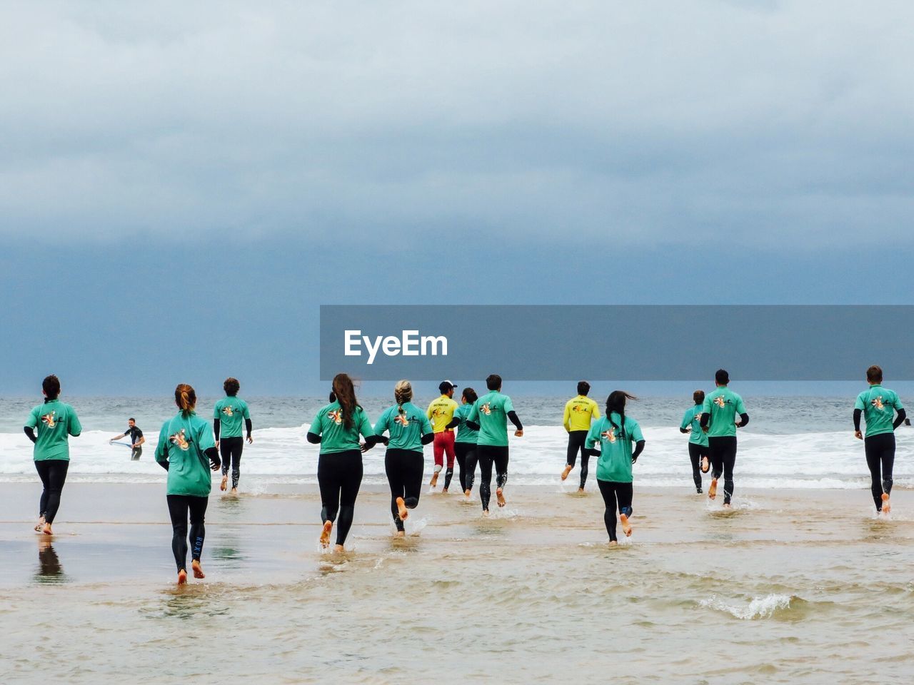 Rear view of men and women running in sea