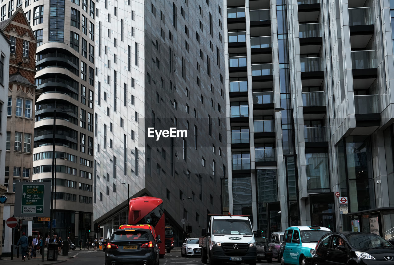 CARS ON CITY STREET BY MODERN BUILDINGS AGAINST CLEAR SKY