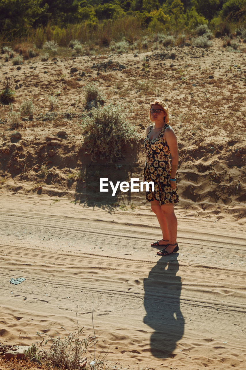 Full length of young woman standing on dirt road