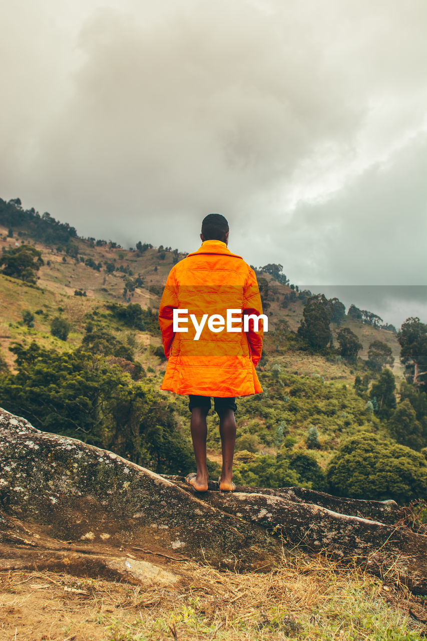 Rear view of a young adult standing against mountain