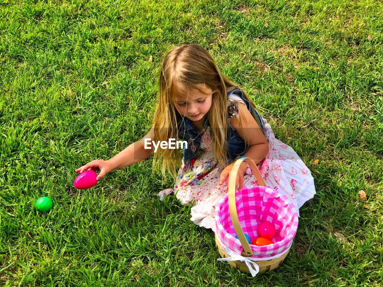 High angle view of girl playing with easter eggs at grassy field