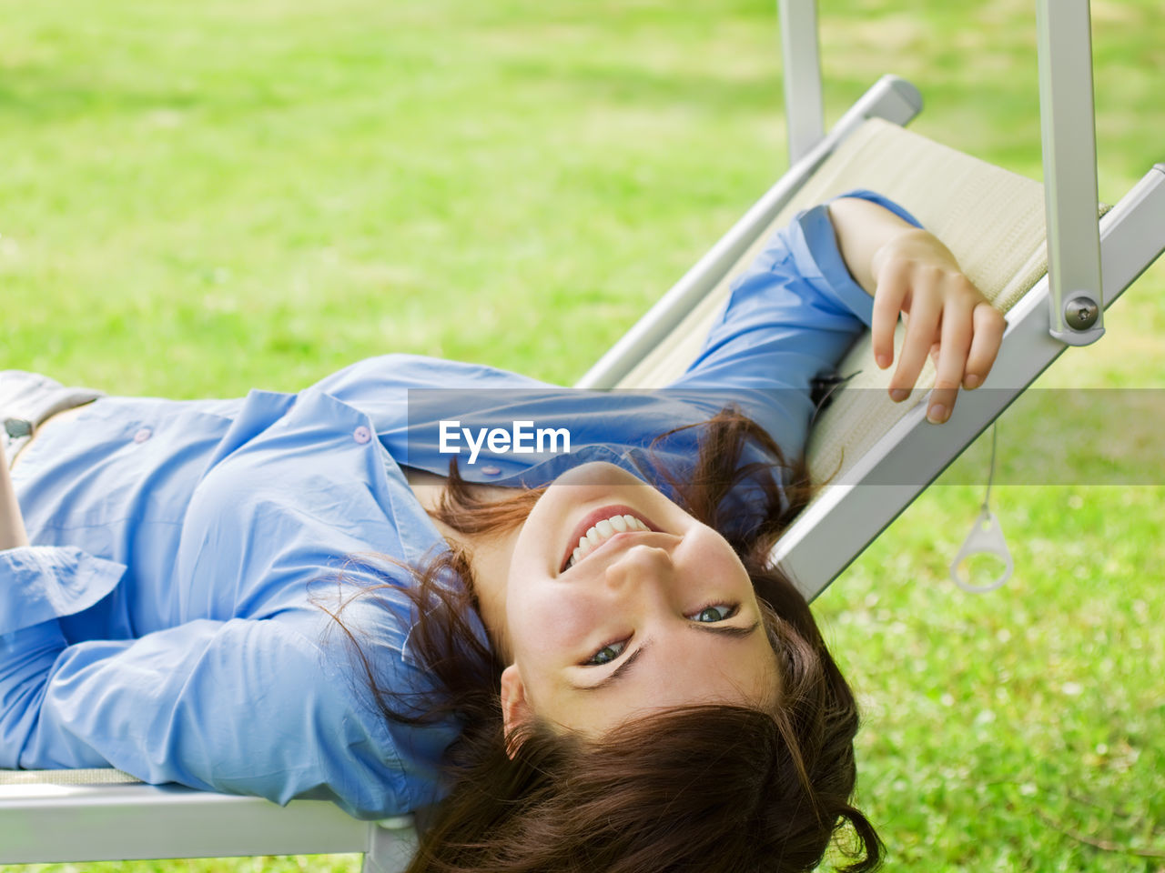 PORTRAIT OF YOUNG WOMAN RELAXING ON FIELD