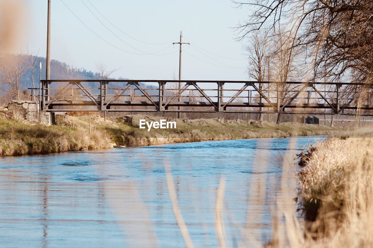 water, river, reflection, nature, sky, architecture, plant, no people, morning, built structure, tree, day, environment, winter, electricity, power generation, shore, bridge, tranquility, landscape, outdoors, cable, land, waterway, bare tree, scenics - nature, technology, reservoir, tranquil scene, beauty in nature, electricity pylon