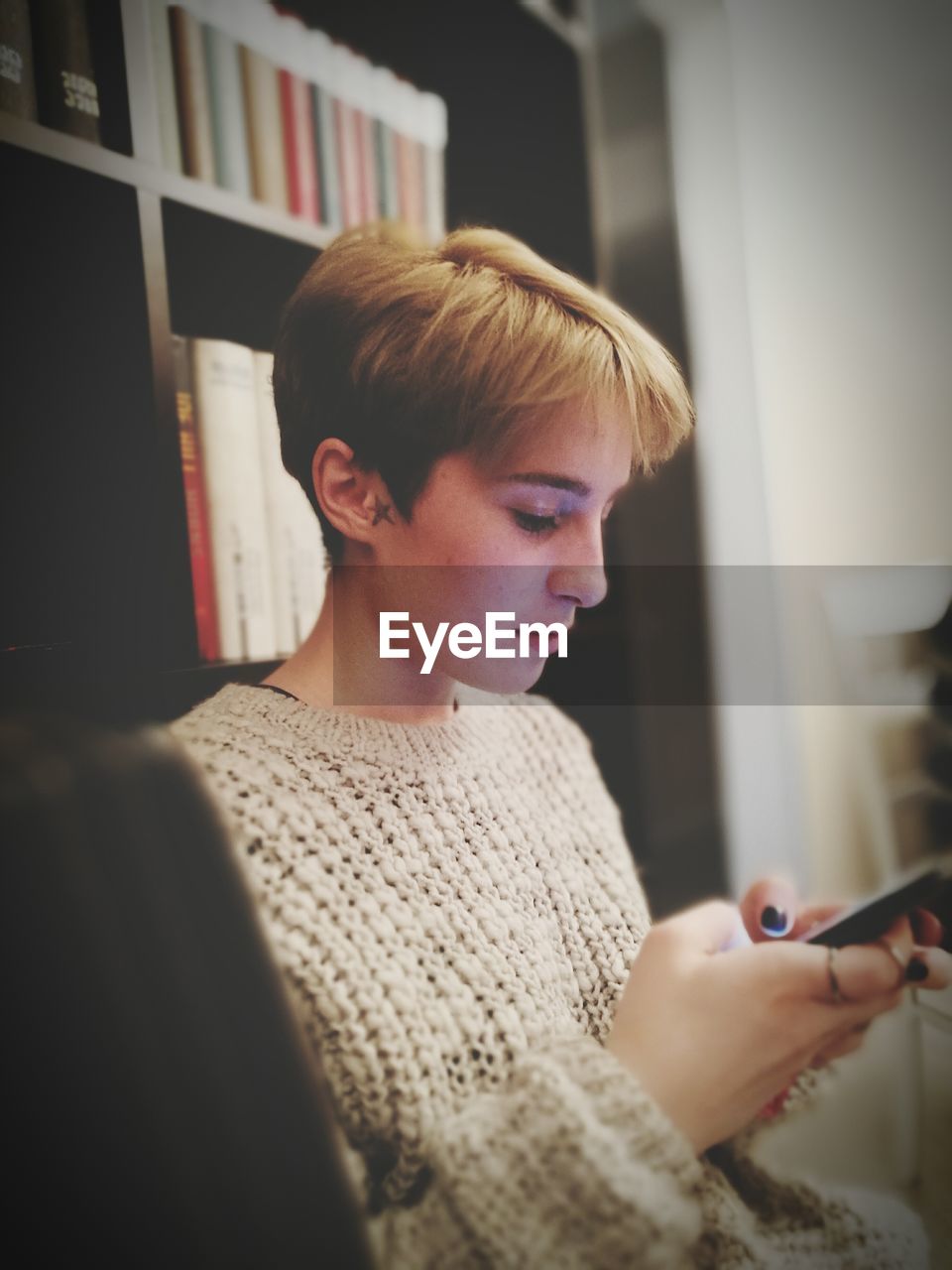 CLOSE-UP OF YOUNG WOMAN HOLDING CAMERA AT HOME IN ROOM