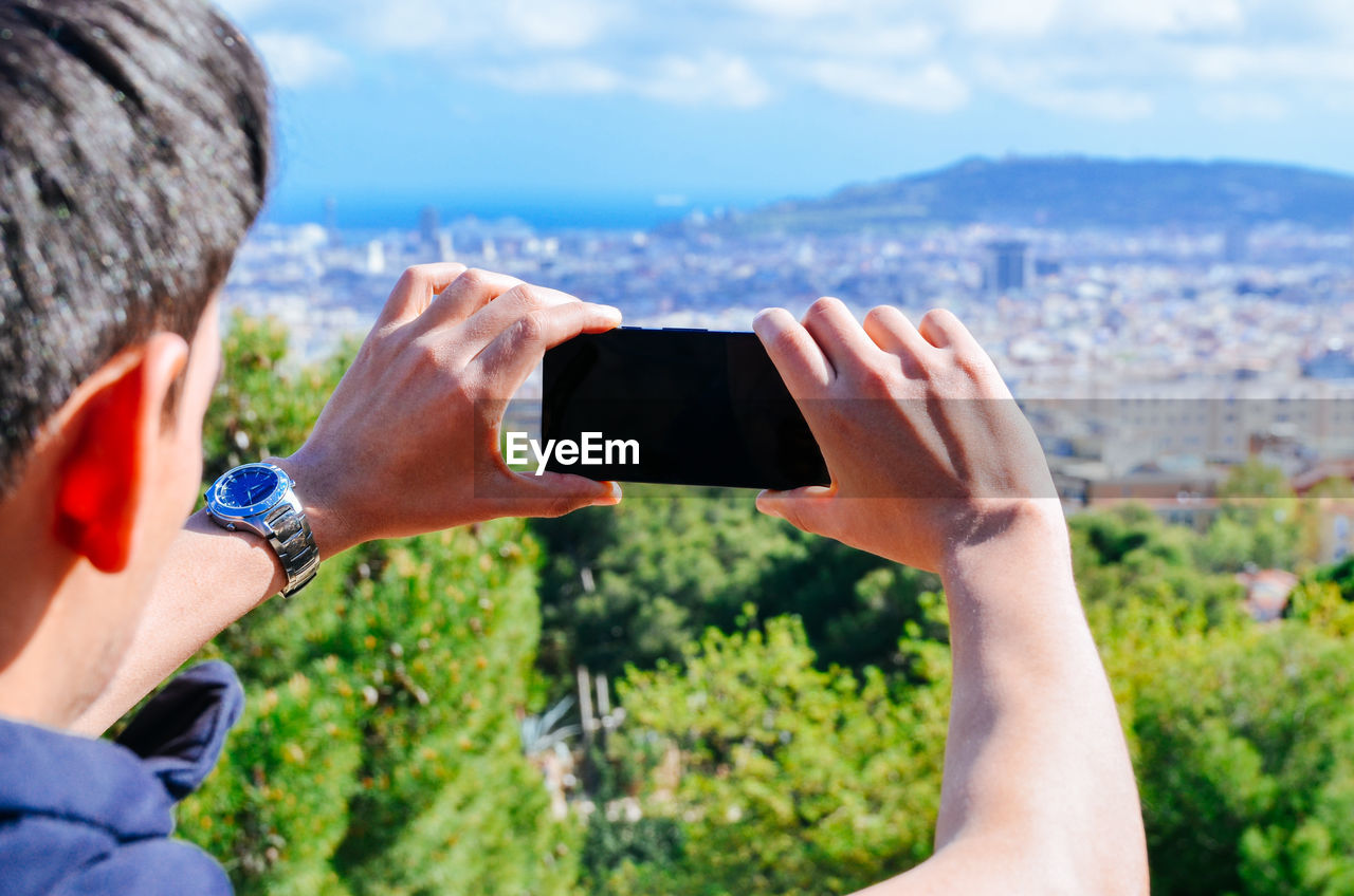 Young man photographing city with mobile phone