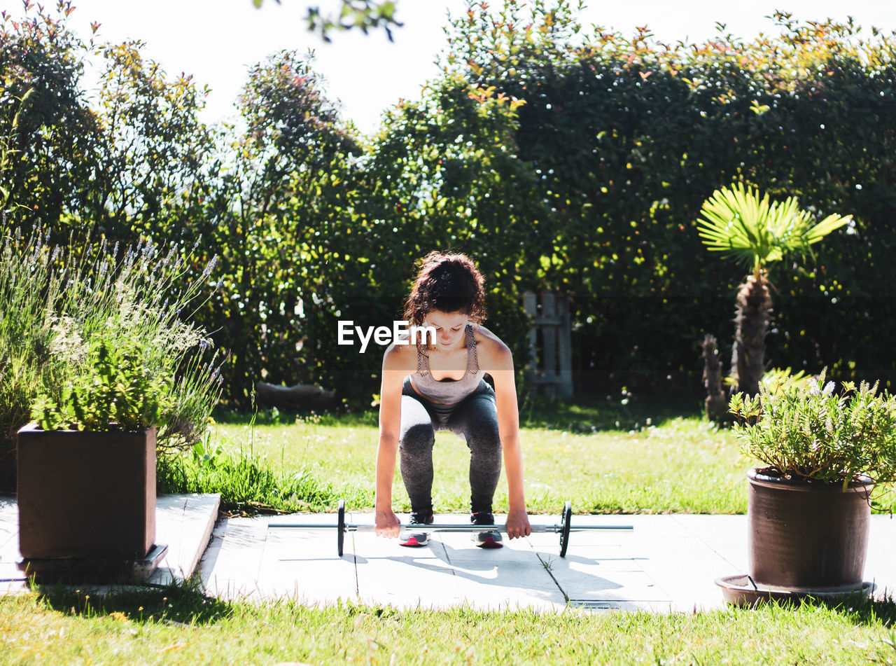 Young woman exercising in her home garden