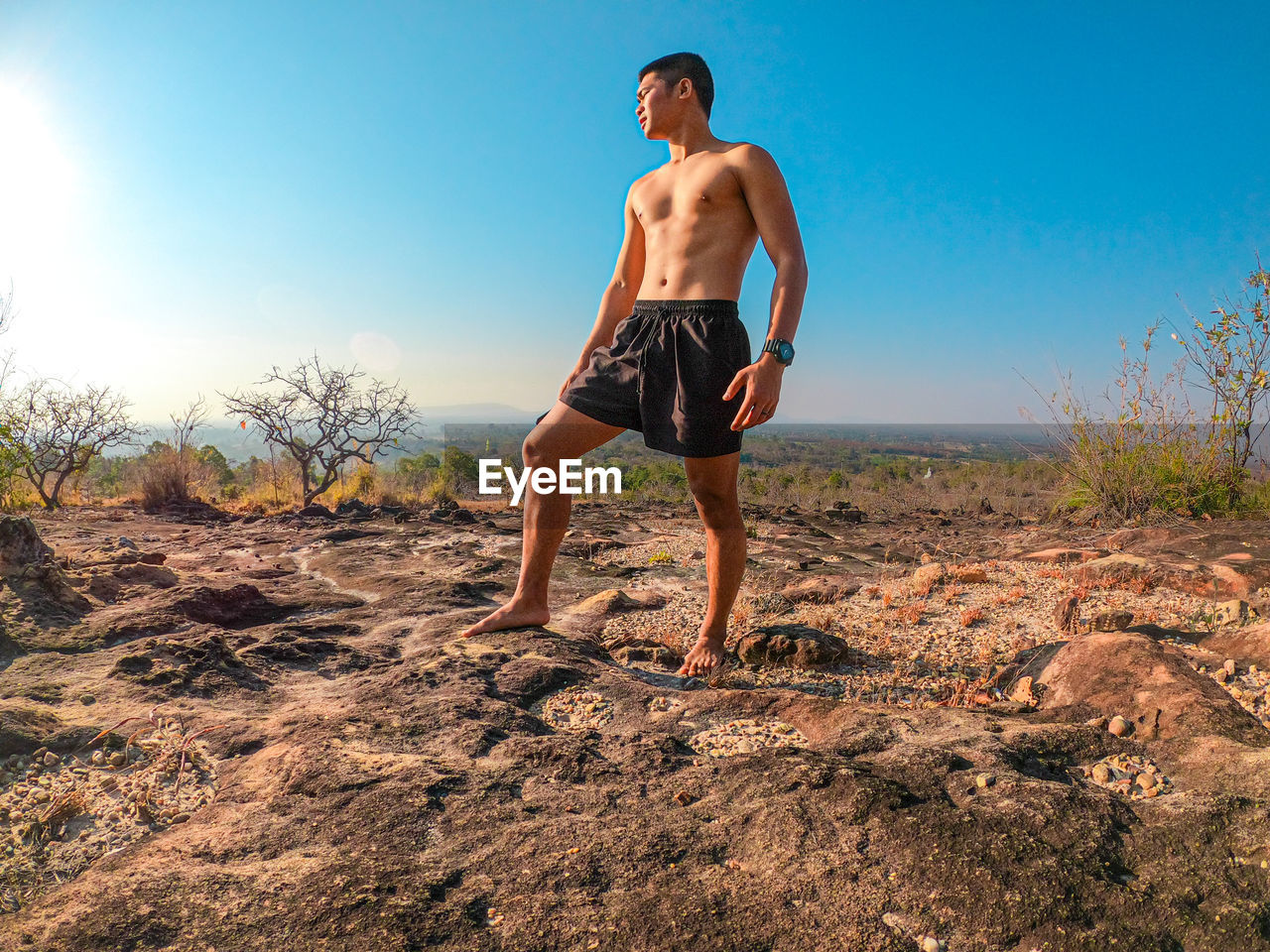 Full length of shirtless man standing on land against sky