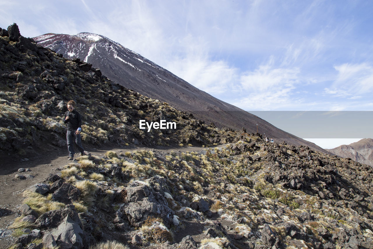 Male hiking a trail in volcanic landscape during a sunny day