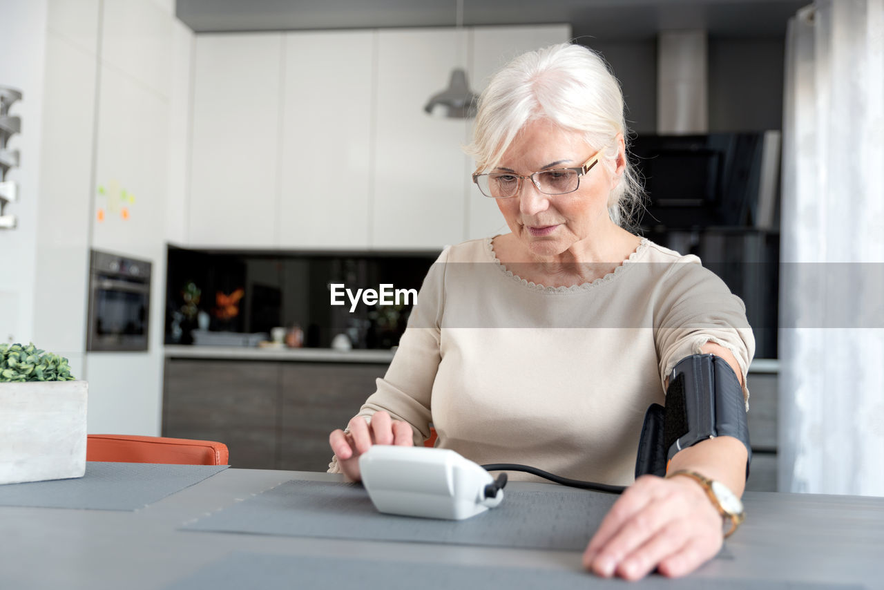 Senior woman checking blood pressure at home