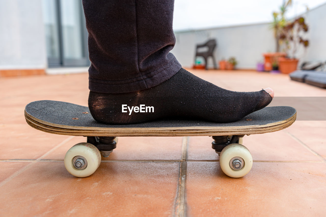 Low section of man standing on skateboard at home