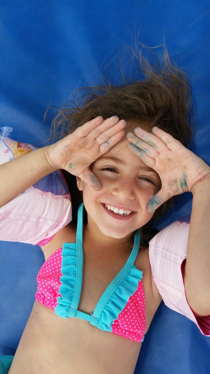 Portrait of smiling girl in bikini top lying on bed