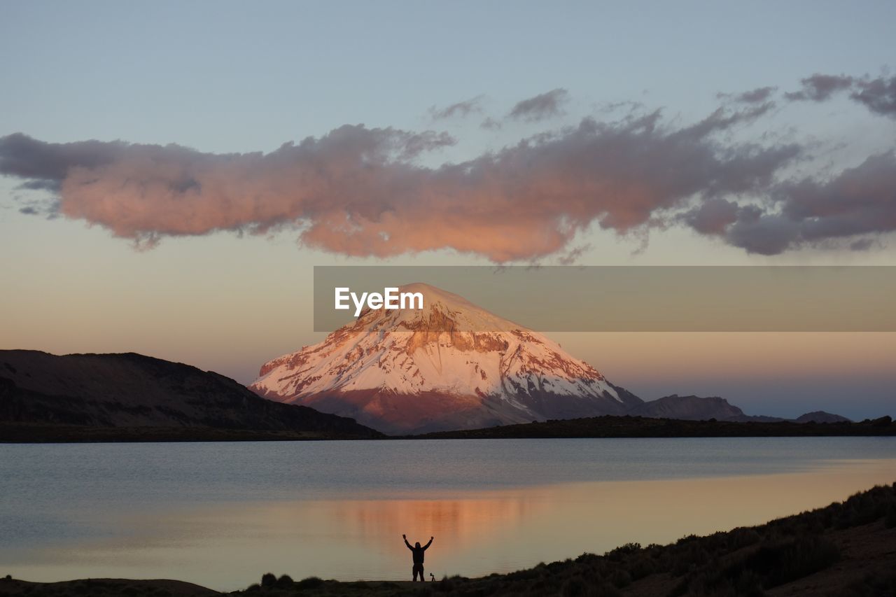 Scenic view of snowcapped mountain by lake during sunset
