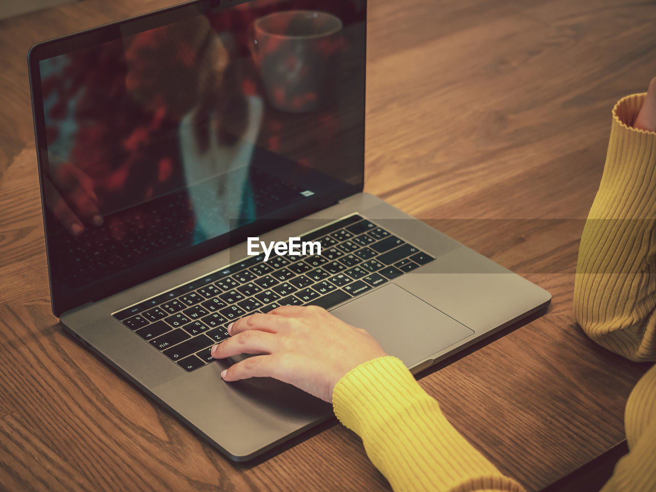 Cropped hands of woman using laptop at table