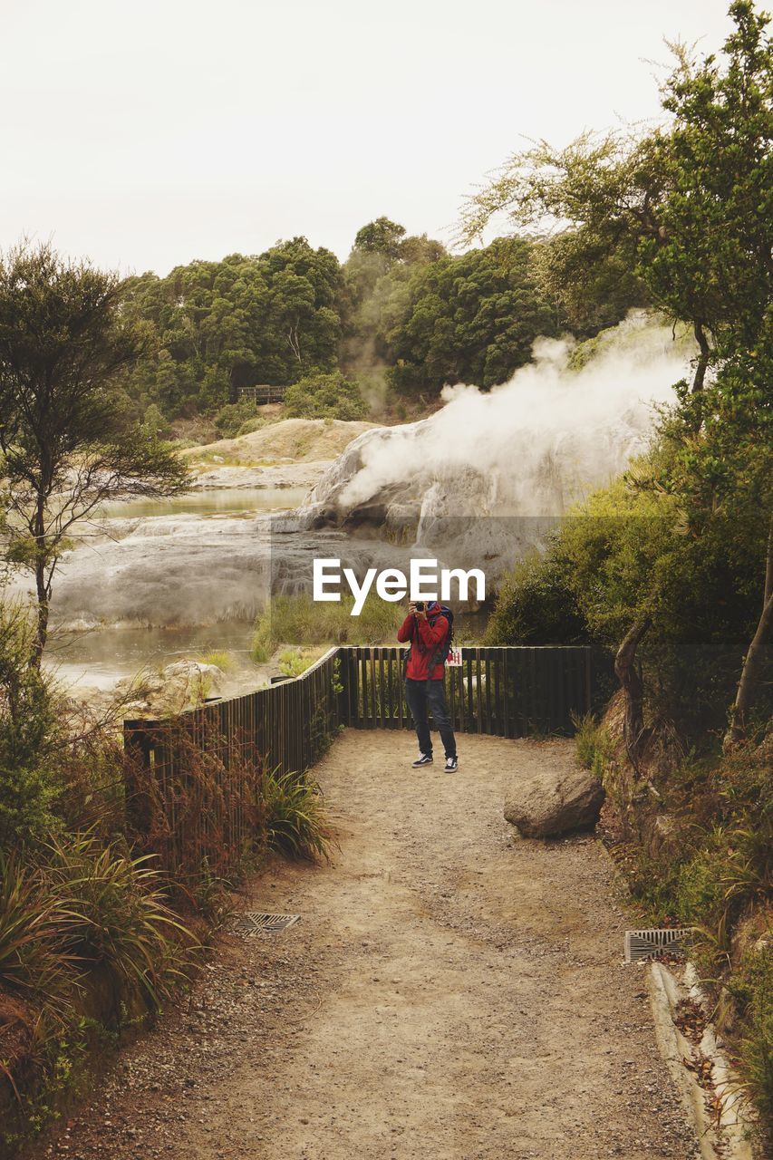 Man with red jacket in a park with a camera 