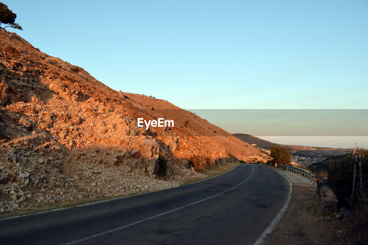 Road by mountain against clear sky