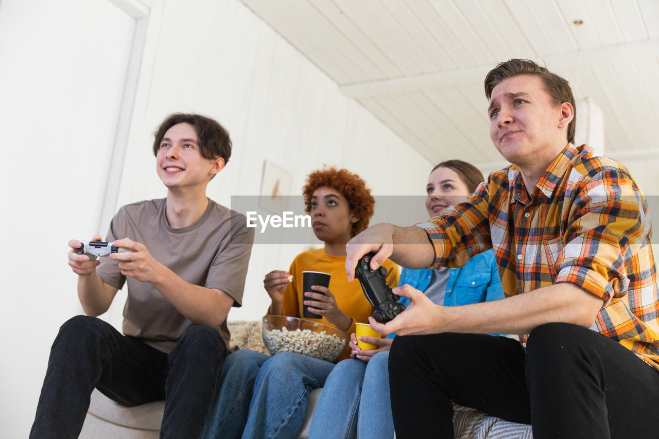 friends using smart phone while sitting on sofa at home