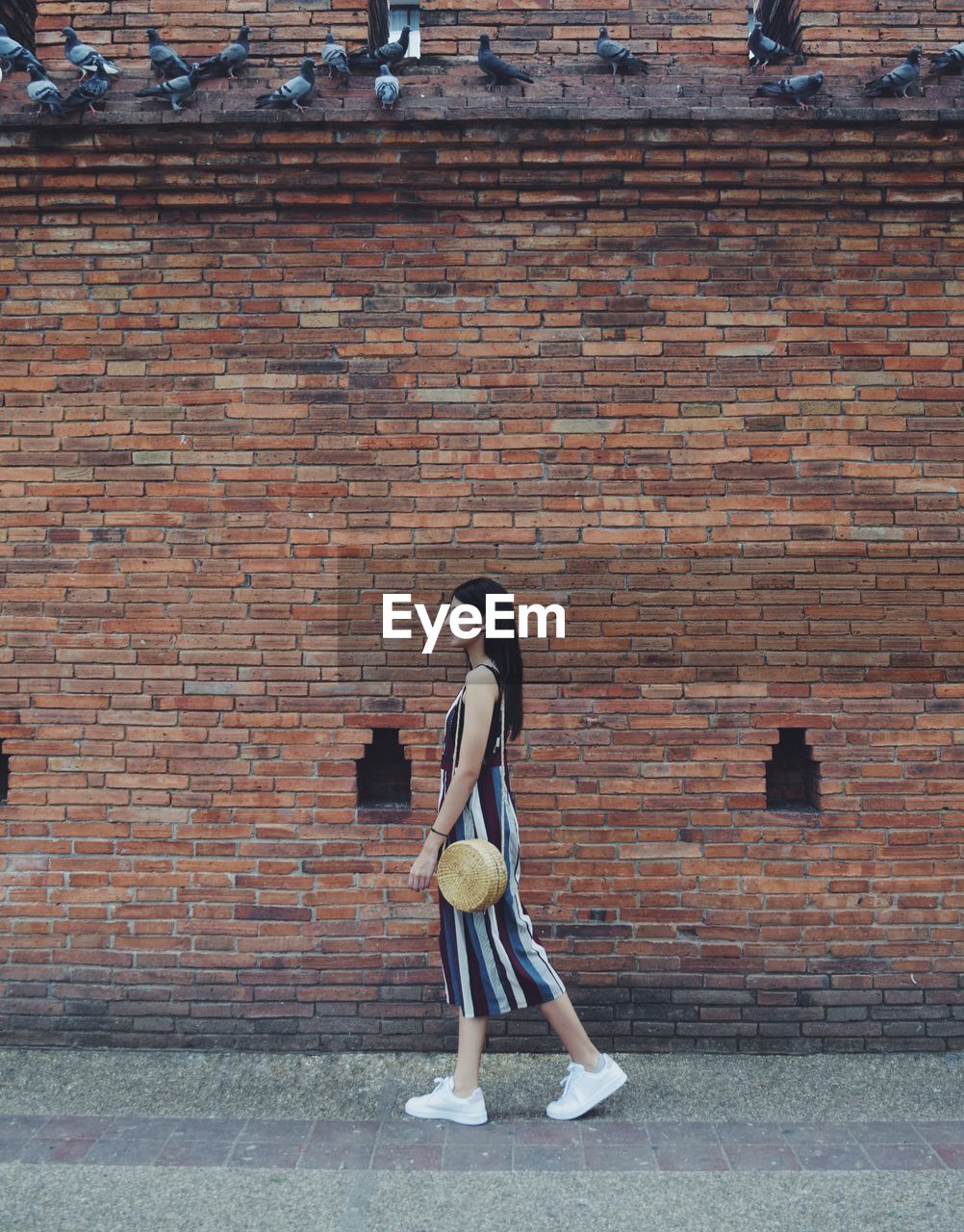 FULL LENGTH SIDE VIEW OF A GIRL STANDING AGAINST BRICK WALL