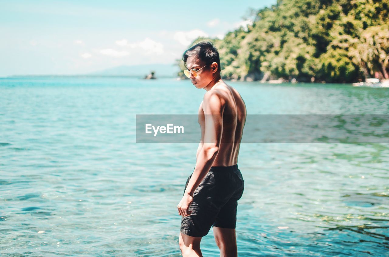 Shirtless man standing in sea at beach