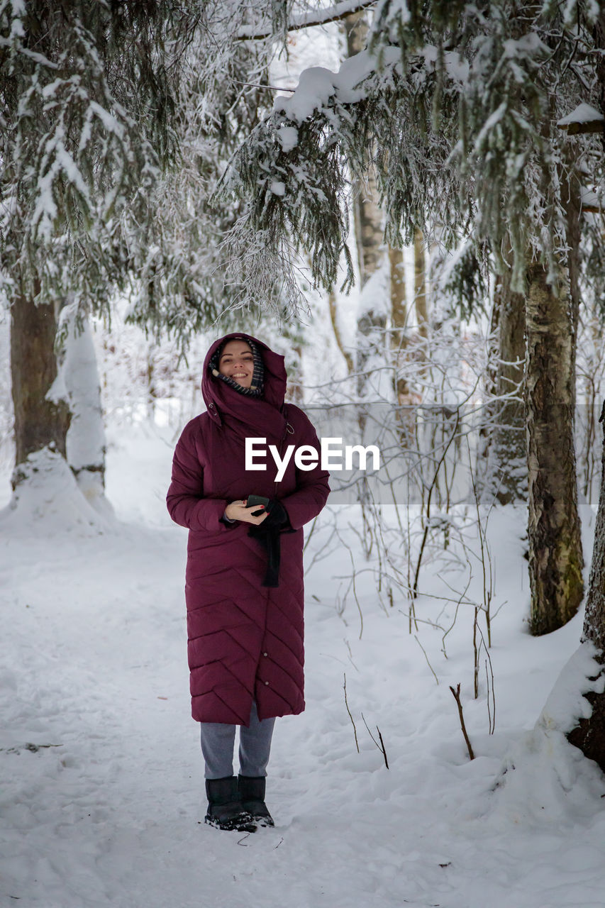 Beautiful woman in a warm coat in winter in a forest covered with snow person