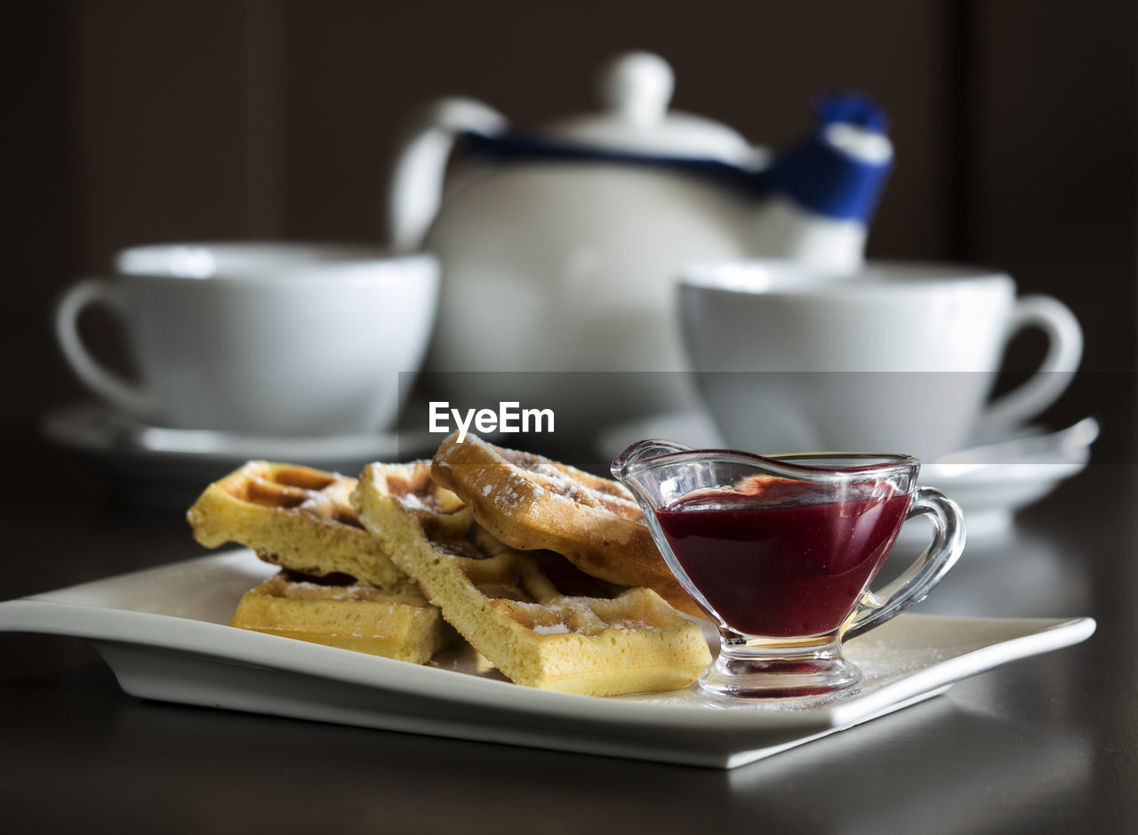 Close-up of belgian waffles with syrup served on table