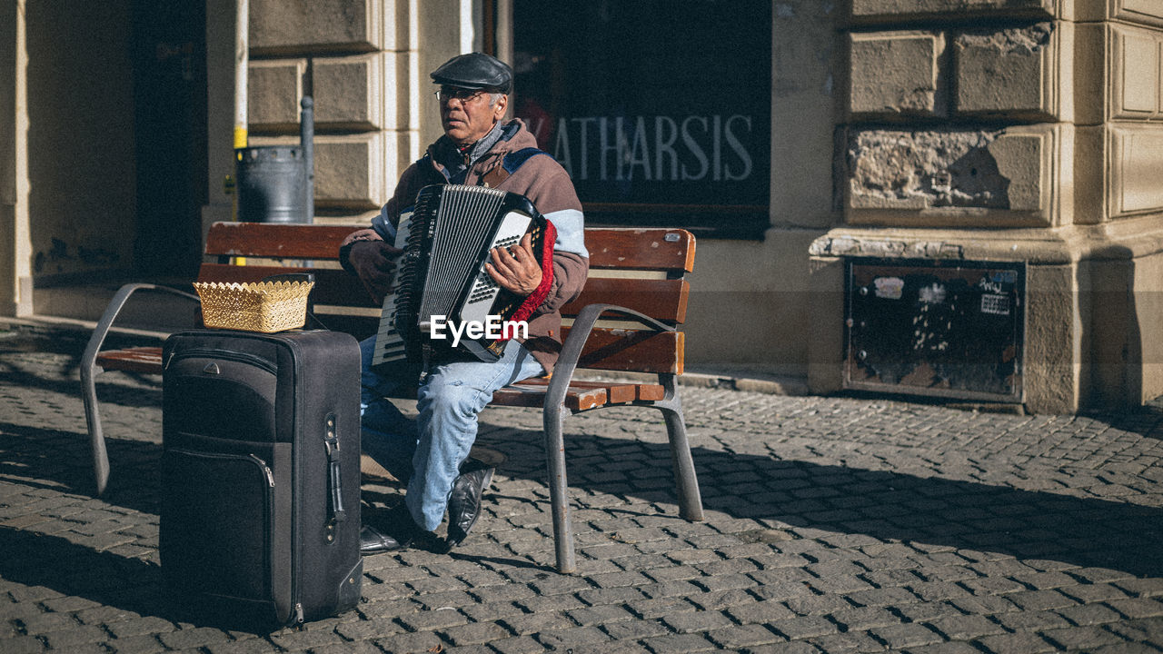 MAN SITTING ON STREET AGAINST CITY