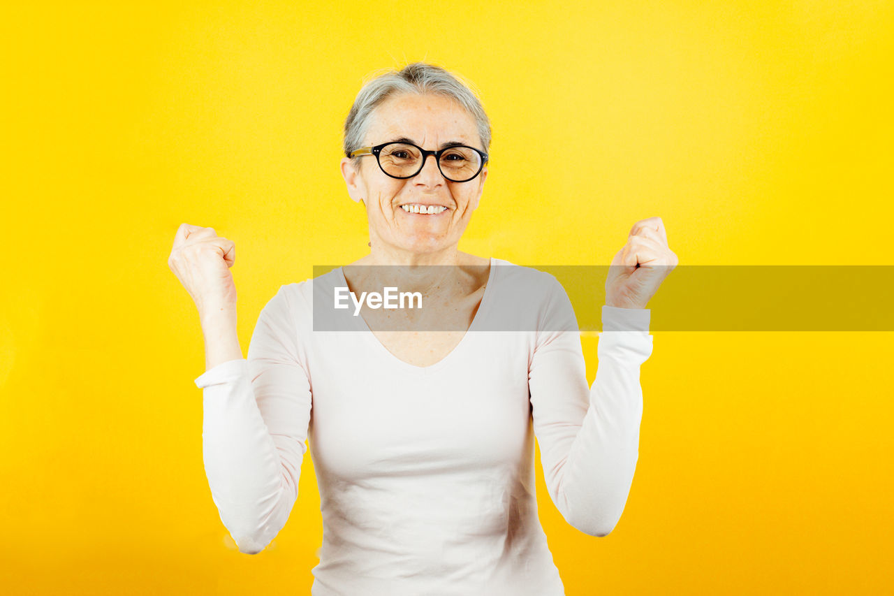 portrait of woman standing against yellow wall