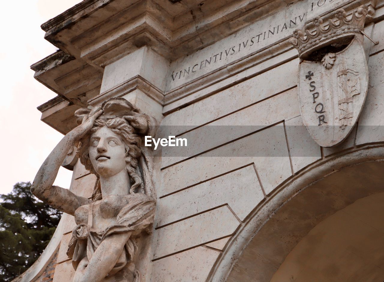 LOW ANGLE VIEW OF STATUE AGAINST BUILT STRUCTURE