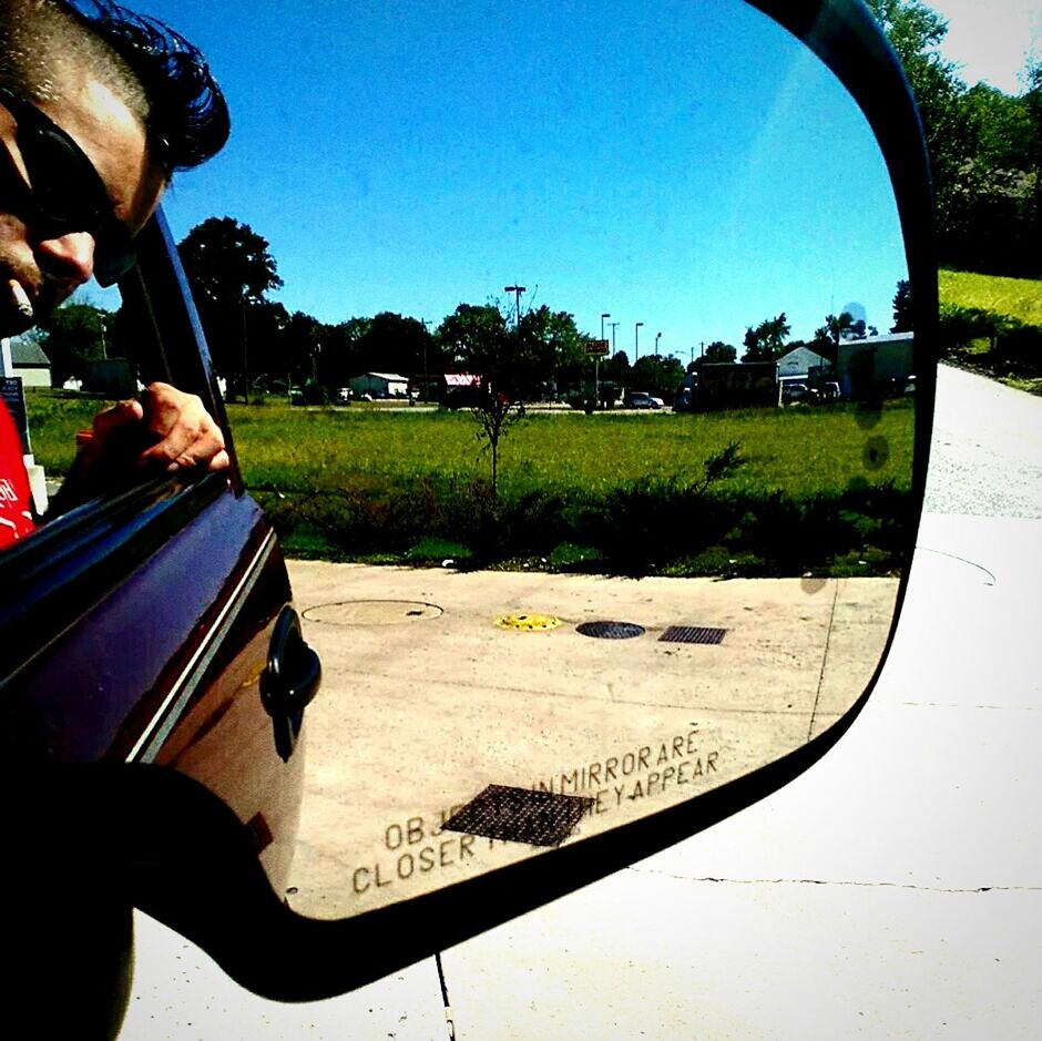 Reflection of man on side-view mirror of car