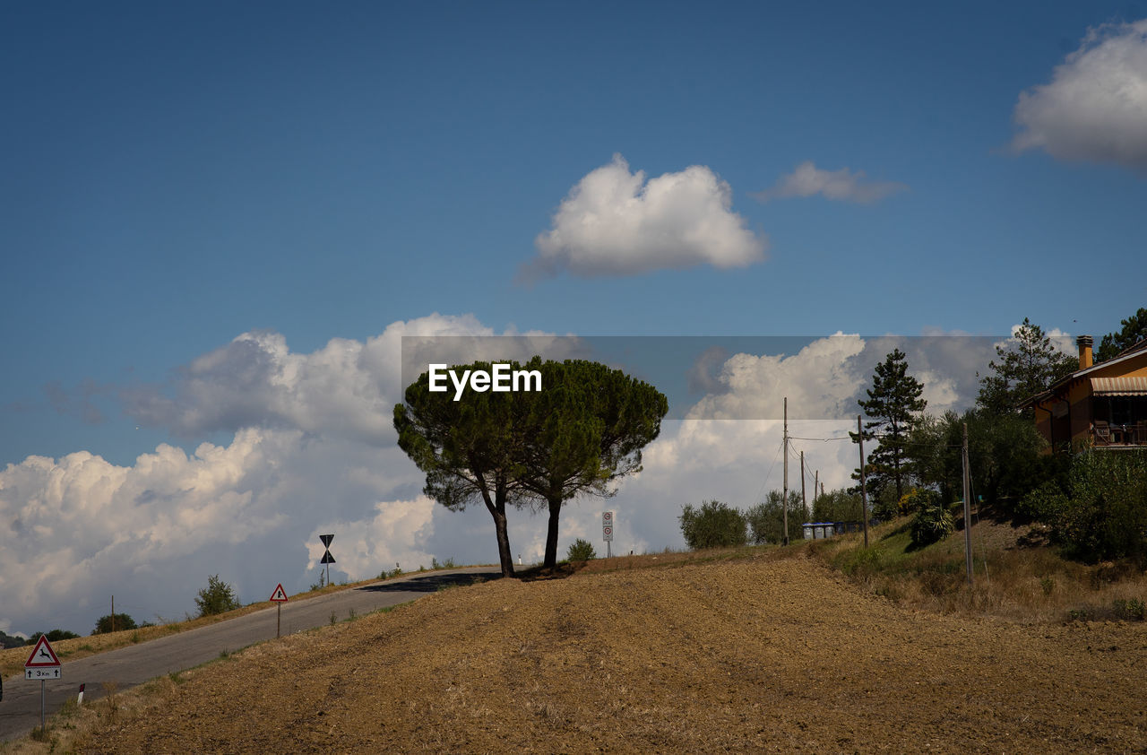 sky, cloud, tree, plant, hill, nature, landscape, rural area, environment, horizon, land, field, soil, scenics - nature, outdoors, beauty in nature, travel, natural environment, blue, no people, travel destinations, day, transportation, tourism, architecture, sand, tranquility