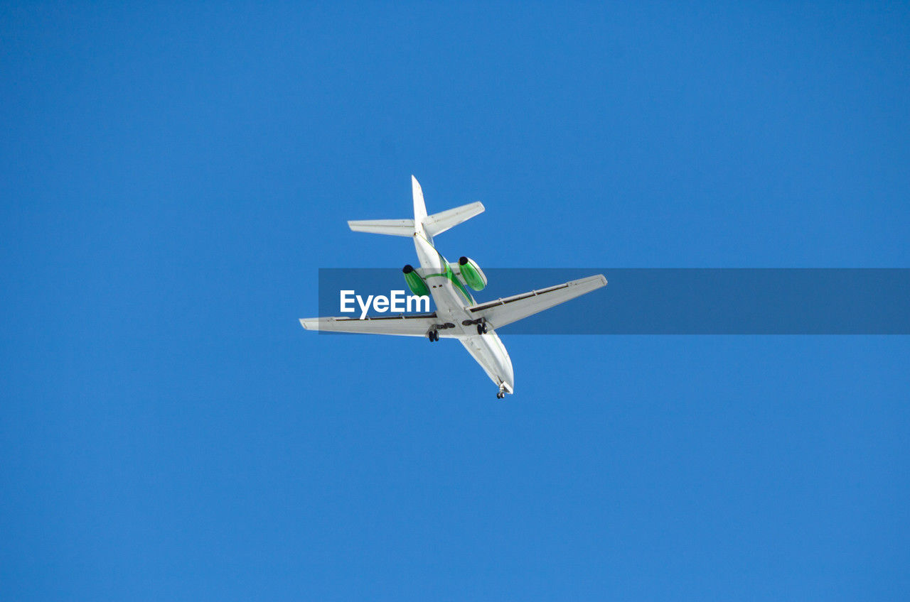 low angle view of airplane flying in clear blue sky