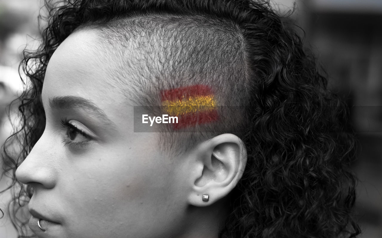 Close-up woman with spanish flag painted on head