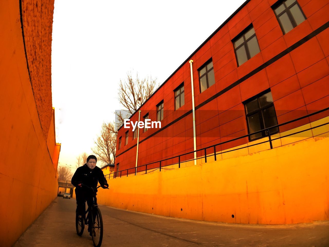 Man cycling on road amidst buildings