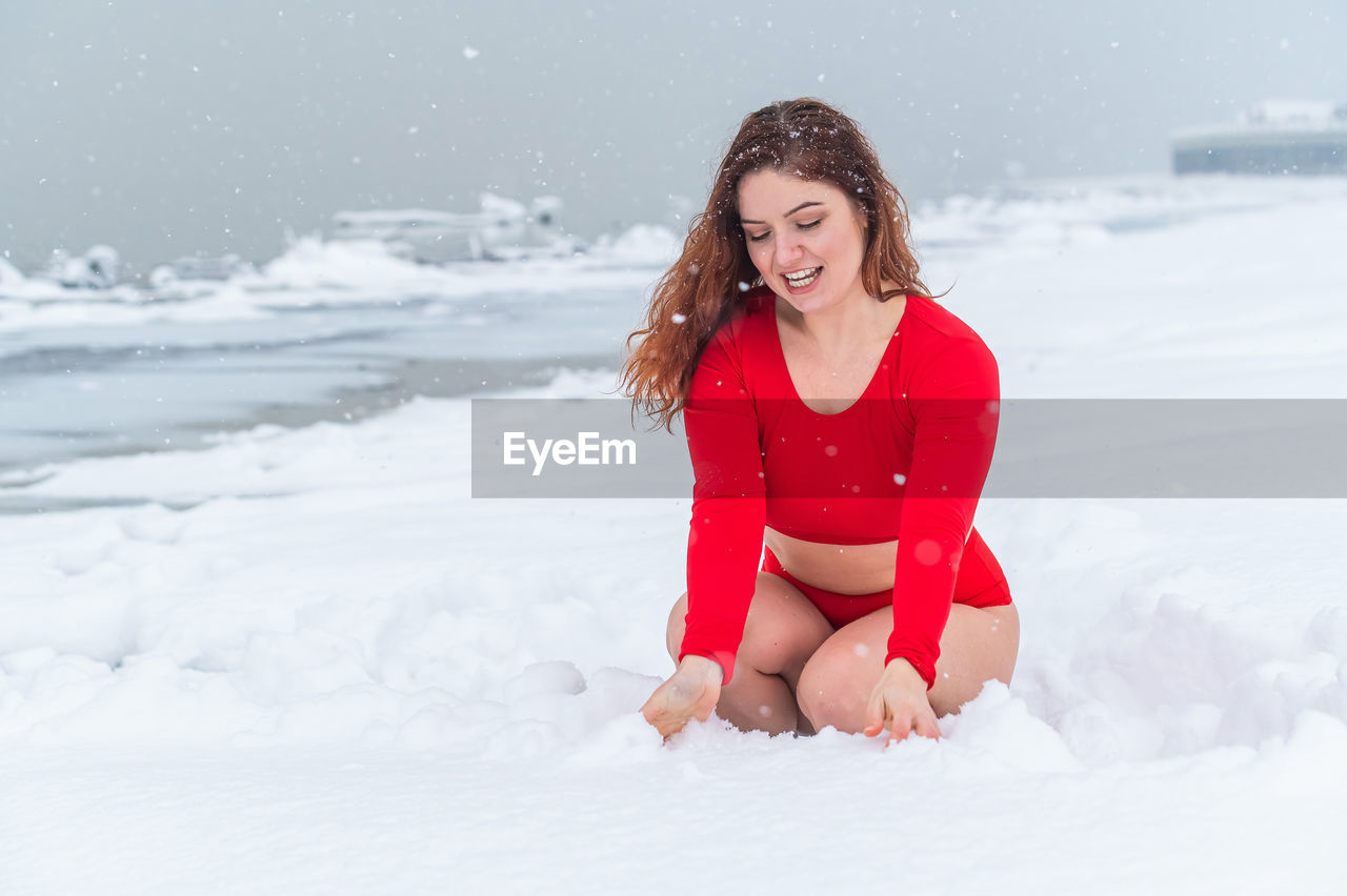 portrait of smiling young woman standing on snow