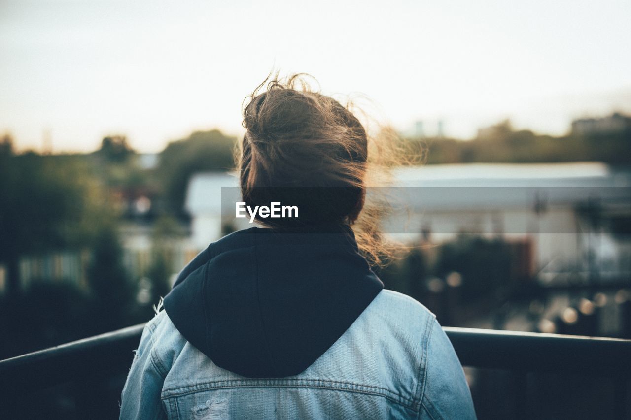 REAR VIEW OF WOMAN STANDING AGAINST SKY