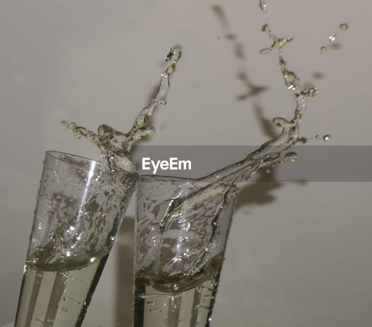 CLOSE-UP OF WATER SPLASHING IN GLASS AGAINST WHITE BACKGROUND