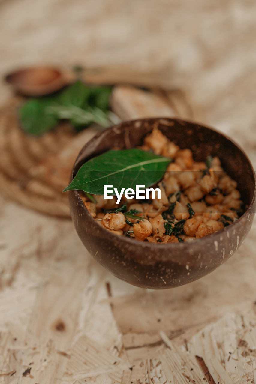 From above of vegetarian chickpea in bowl and slices of bread placed on table with basil for delicious lunch