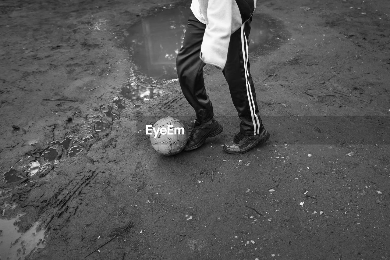 Low section of man playing soccer by puddle on field