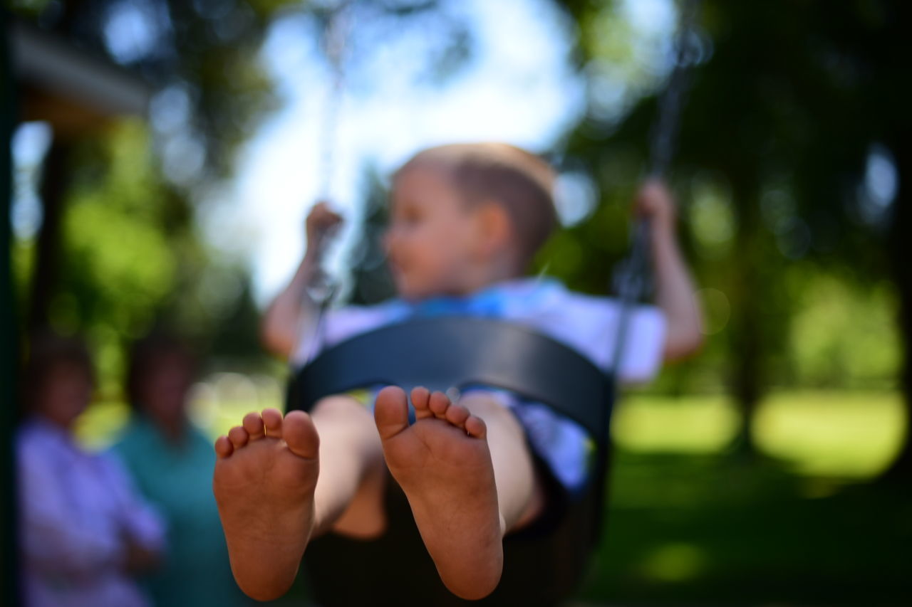 CLOSE-UP OF BOY PLAYING WITH BLURRED OUTDOORS