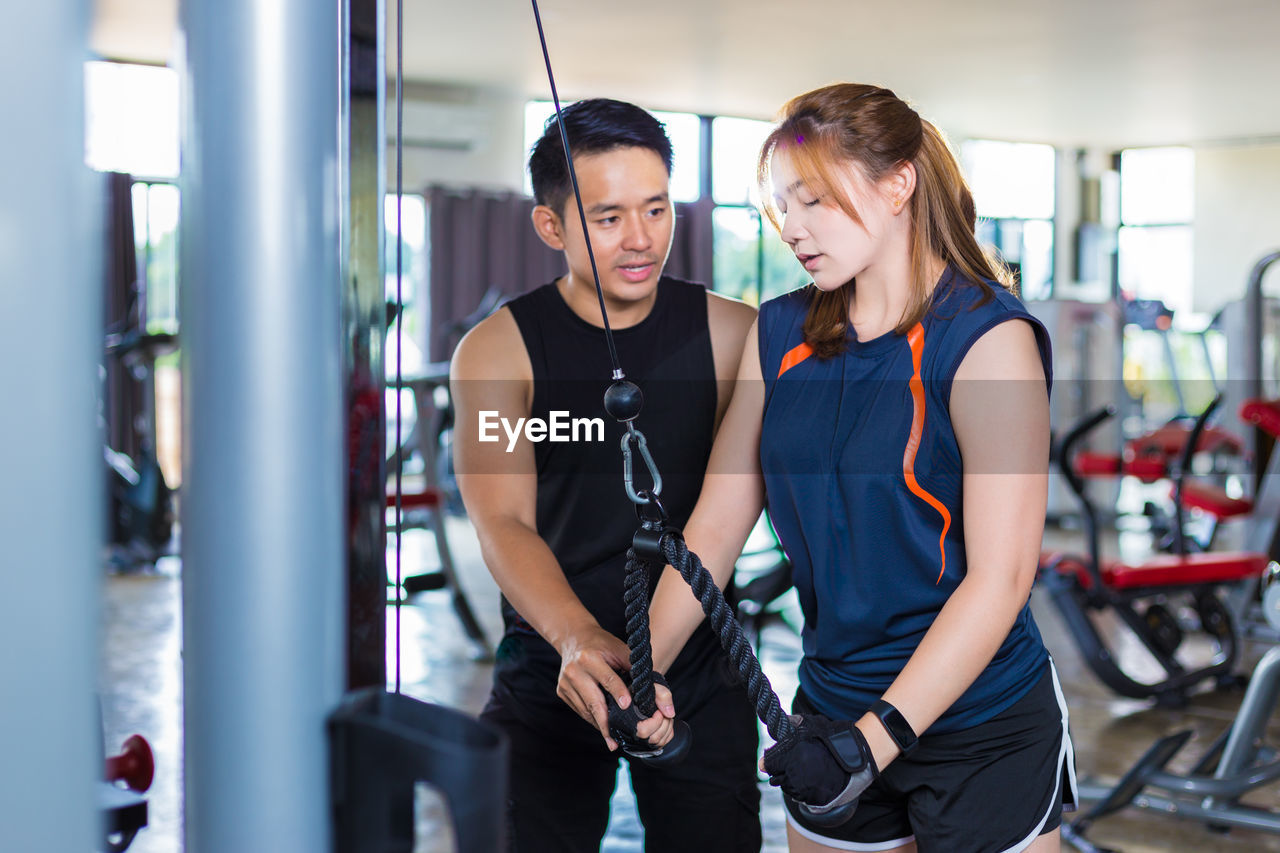 Instructor teaching woman exercising in gym