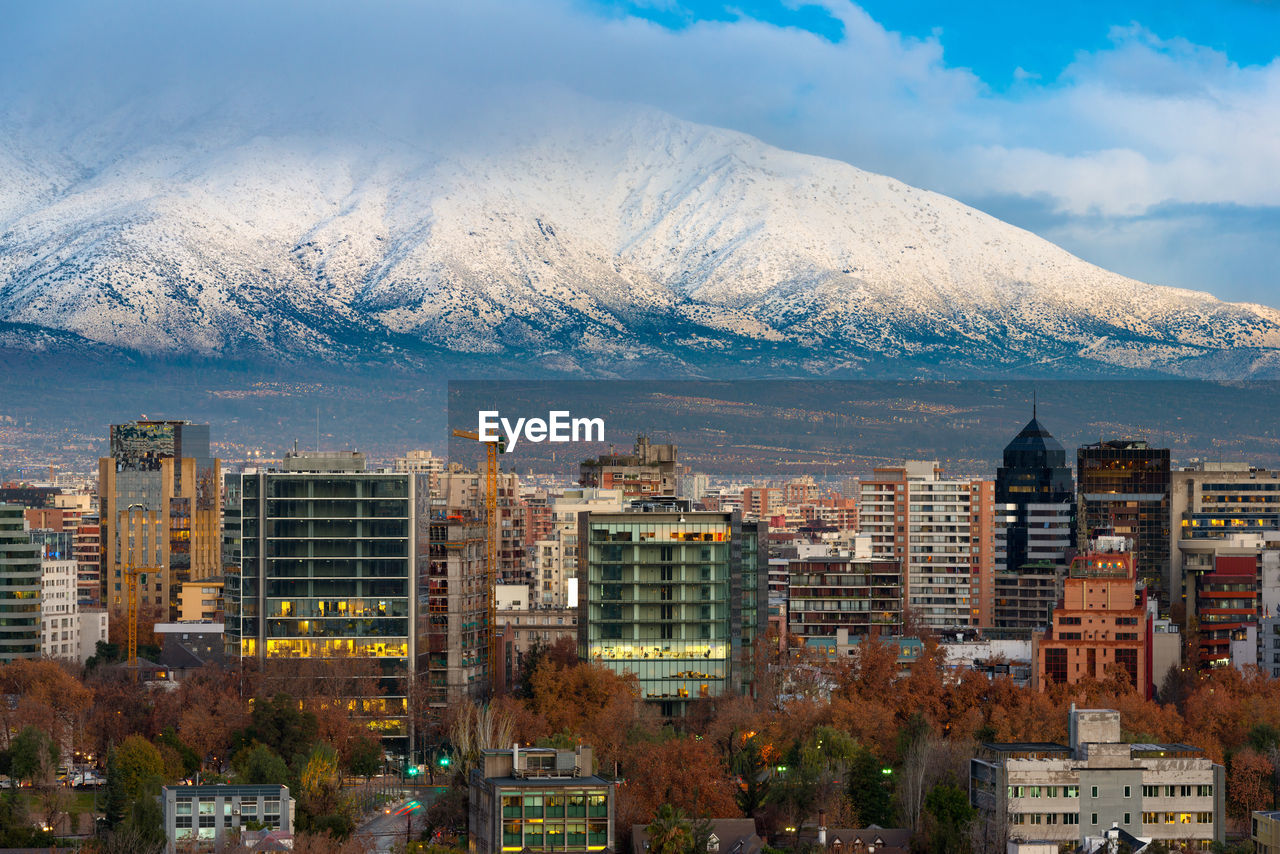 Buildings in city against snowcapped mountain