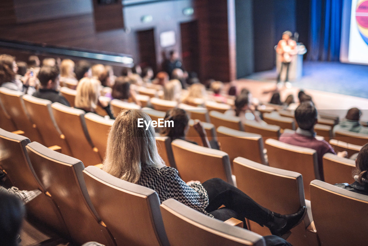 audience, auditorium, lecture hall, sitting, adult, group of people, women, seat, student, education, crowd, seminar, conference hall, convention, indoors, learning, school, university student, chair, university, men, young adult, meeting, talking, large group of people, architecture, arts culture and entertainment, female