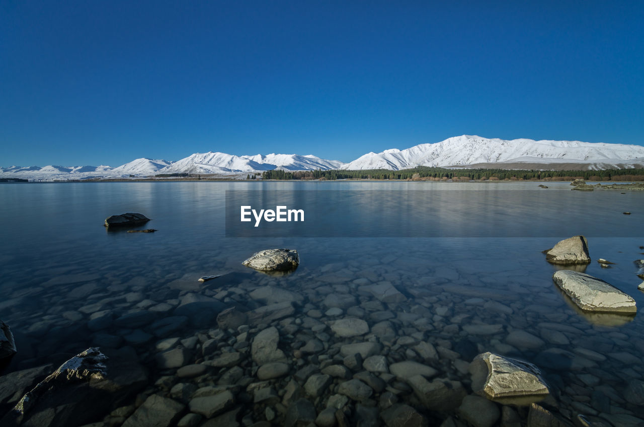 Scenic view of frozen lake against clear blue sky