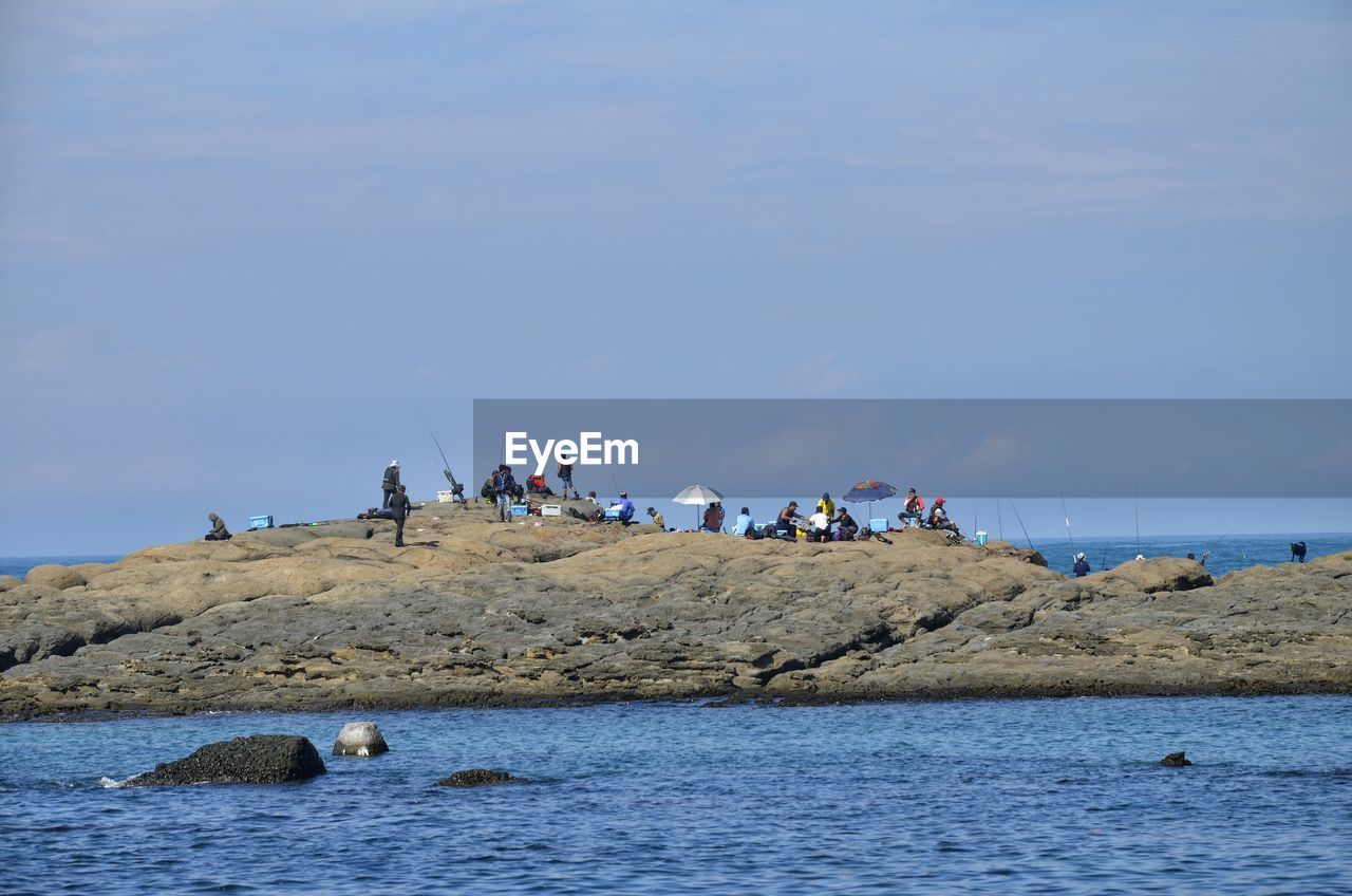 People gathered on huge rock amidst sea