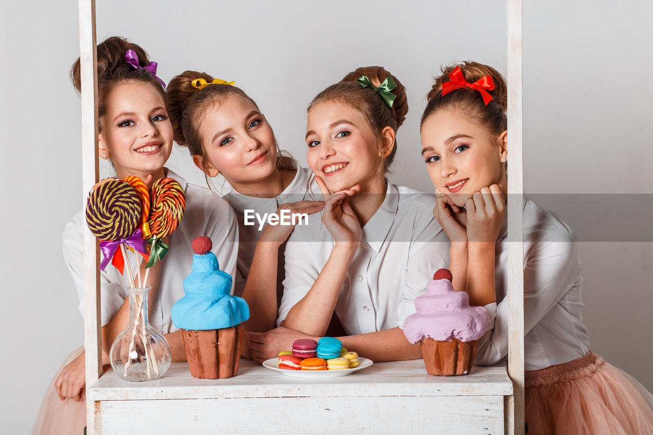 Portrait of happy friends with sweet food against white background