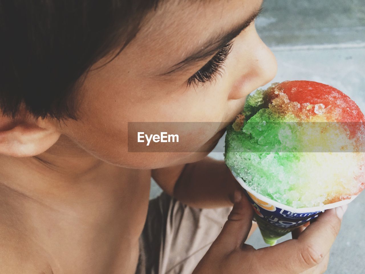 High angle view of shirtless boy eating colorful ice cream