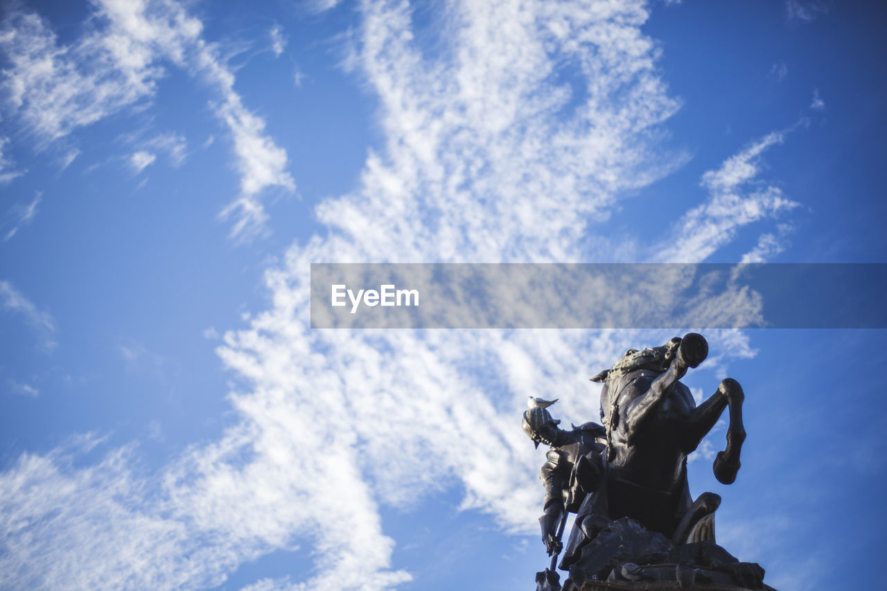 Low angle view of statues against cloudy sky