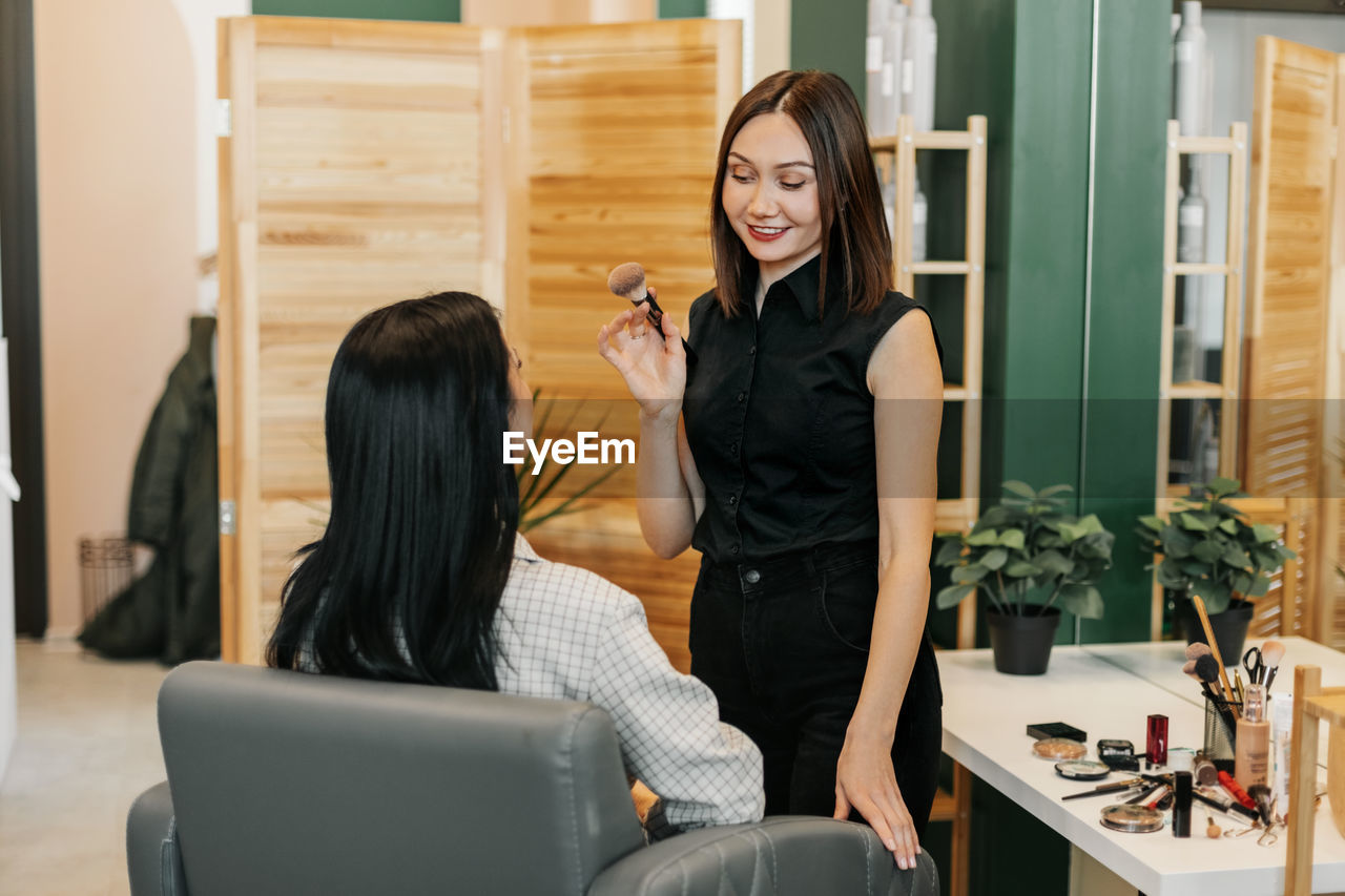 The makeup artist girl applies powder or blush to her client, completes the image. beauty, makeup